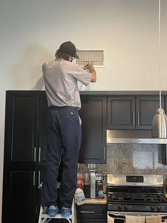 Technician inspecting an air vent during HVAC service in Highland Springs